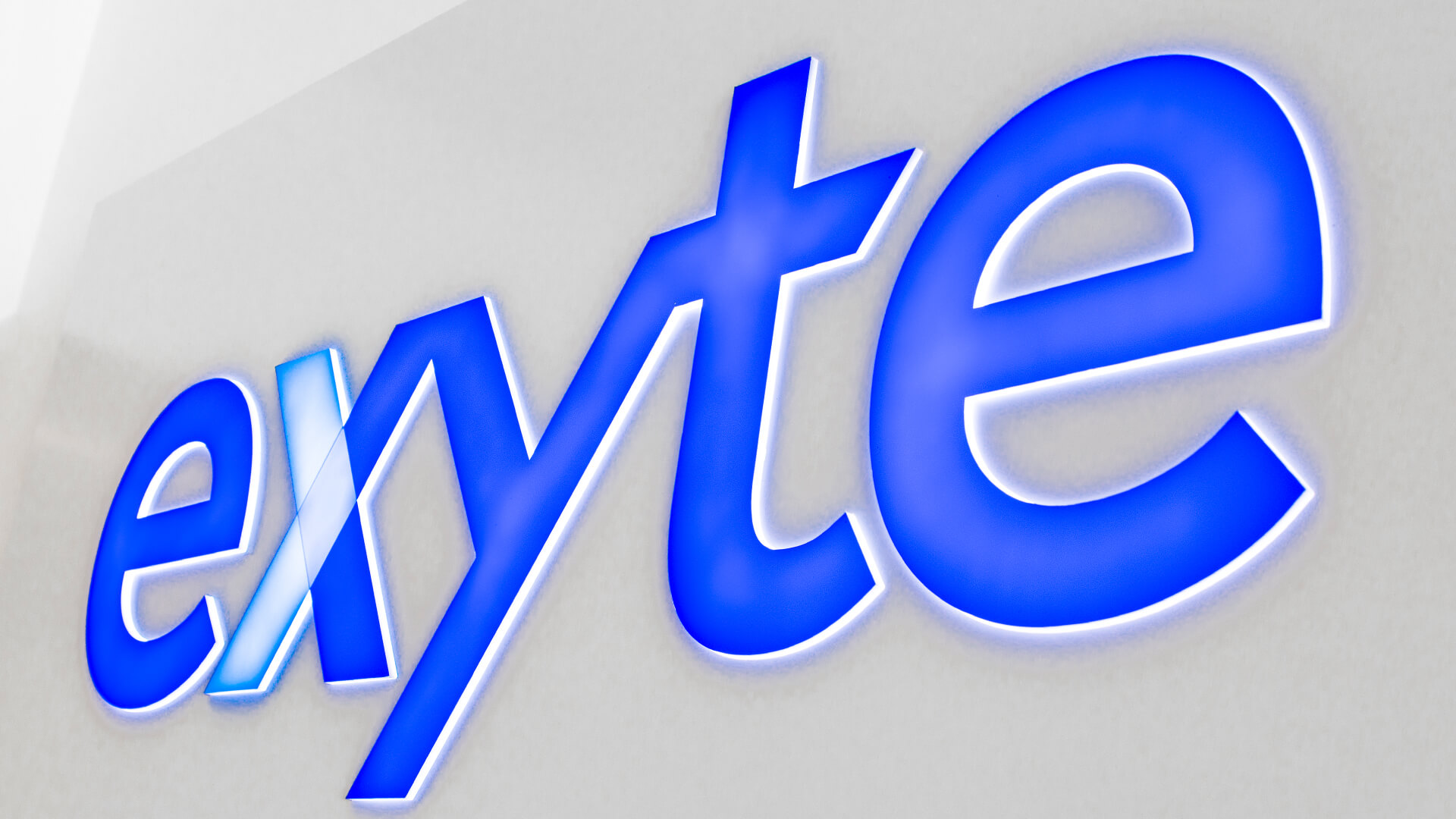 Exyte-Ausgang - exyte-kassentafel-an-der-wand-innen-des-büros-hinter-der-rezeption-blaues-logo-hintergrundbeleuchtete-kassentafel-für-bestellungen-gdansk-park-technologisch-wissenschaftlich